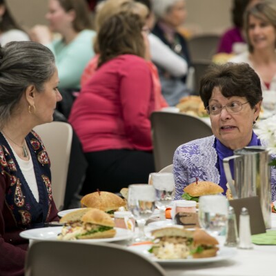 Two women sitting at a table, speaking to one another.