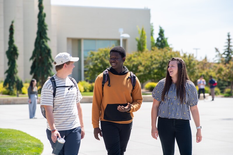 Three students walk through the Taylor quad on campus.