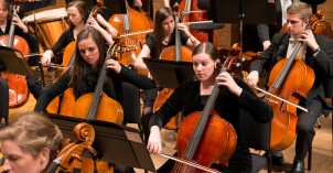 Students play cellos in a symphony orchestra.