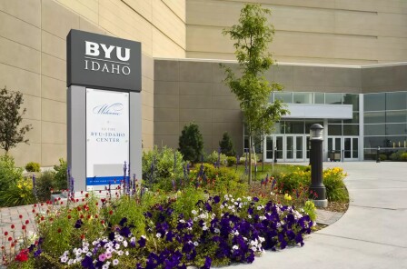 A east view of the BYU-Idaho Center, which displays a Welcome to BYU-Idaho sign, surrounded by flowers and trees.