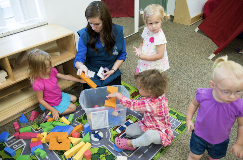 A BYU-Idaho student, Child Lab teacher and small children playing with blocks during Child Labs.