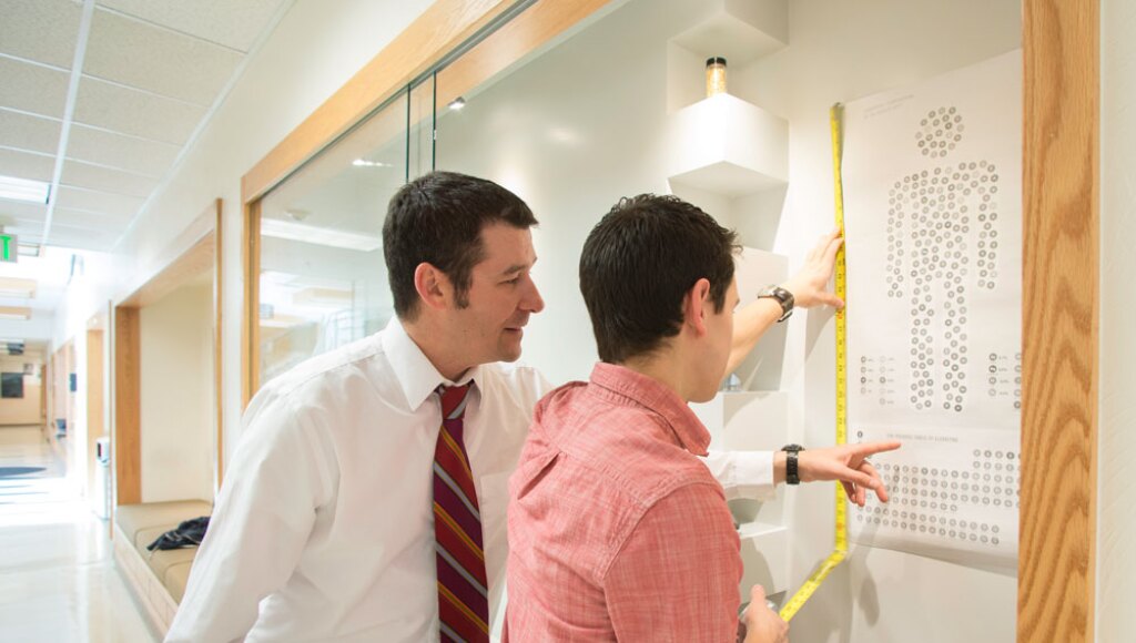 A teacher and student and BYU-Idaho discussing elements of the display case in the Romney Building.