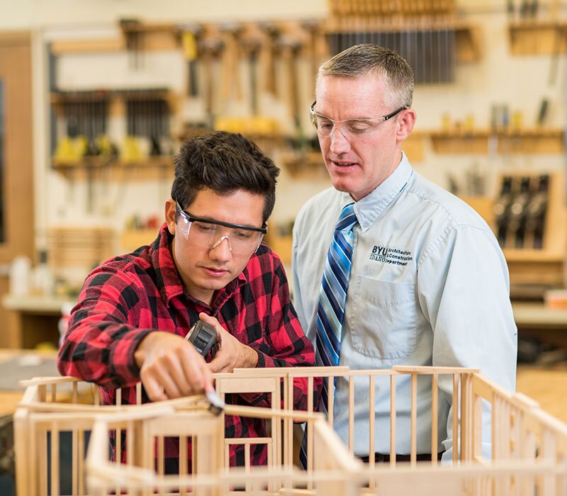 A teacher helping a student on his woodworking project.