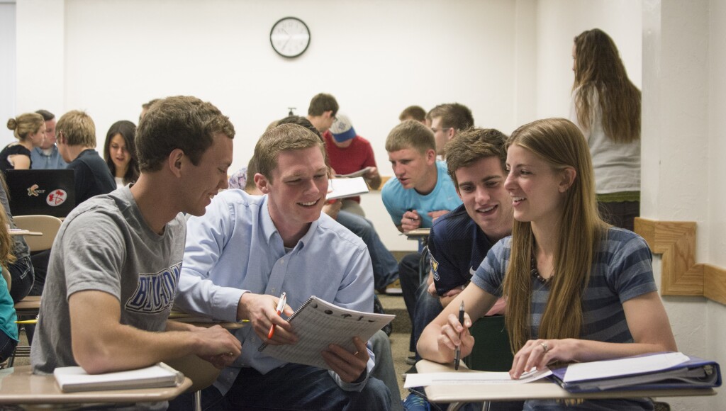 Three male students and one female student sit at desks and teach each other during a teaching session in an Essentials of Human Nutrition class.