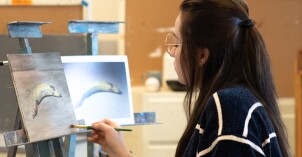 An artist paints a still life in class of a browning banana.