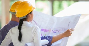Two construction workers look at a blueprint.