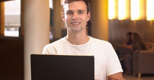 A Digital and Social Media student sits in the I-Center on their computer and smiles.