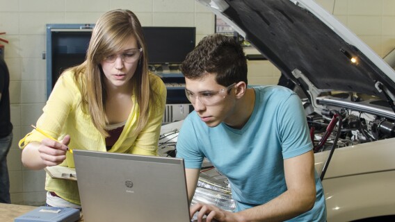 Students look at a computer in the Automotive Lab.