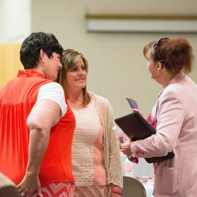 Three women standing together, talking with one another at the University Women's Association.