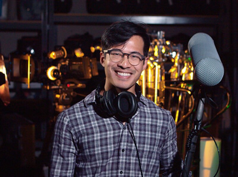 A Video Production student holds a mic and other equipment while smiling.