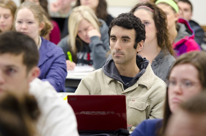 A male student listens with interest to a faculty member during a Foundations Science class for his General Studies degree.