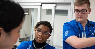 A group of three nursing students practicing in the nursing lab.