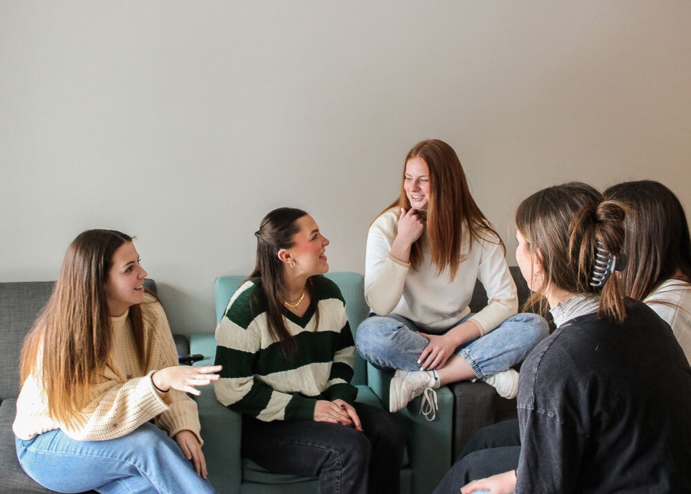 Roommates talking together in their apartment living room.