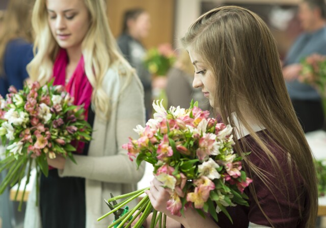 Two female students practice making bouquets in Ben Romney's Floral Design class