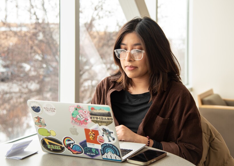 A BYU-Idaho student working on her laptop while on campus