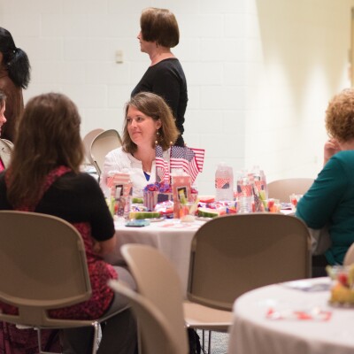 Women sitting around tables, speaking to one another at the Women's Luncheon.