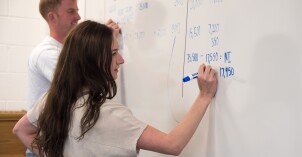 Accounting Students work to balance equations on a whiteboard.
