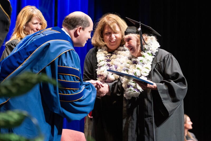 An elderly graduate receives her diploma during a convocation at BYU-Idaho in July 2024.