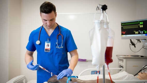A nursing student practicing inserting an IV on a dummy arm