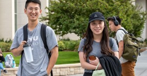 BYU-Idaho students walking through campus and smiling at the camera.