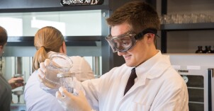 A male student working on a project in the Food Science Research Lab with two other students in the background.