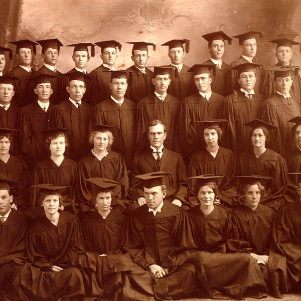 A vintage photograph from the 1900 of four rows of 31 male and female students in graduation robes.