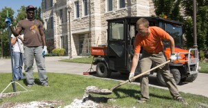 Several students clean up debris on the grass at BYU-Idaho after a heavy thunderstorm.