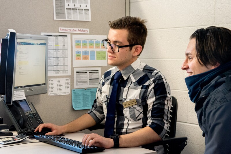 A student receiving help from an Academic Advisor. Both people are looking at a computer desktop screen.