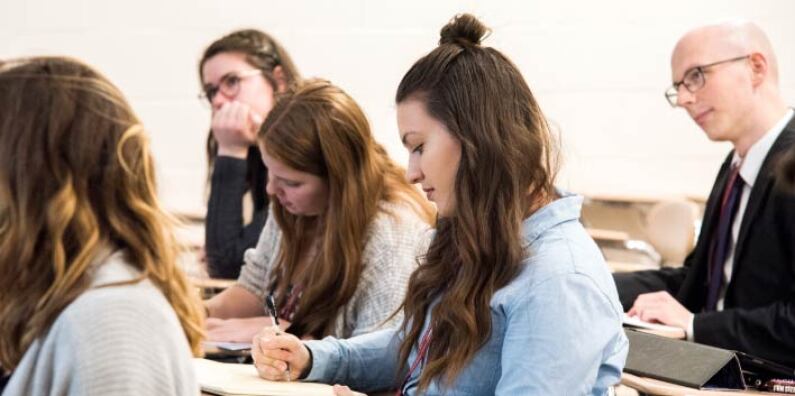 A student takes notes at a desk during a workshop.