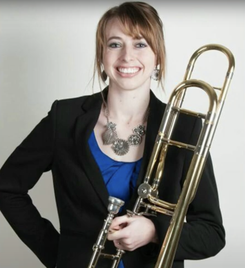 Alexis Smerdon holds a trombone while smiling for a photograph.