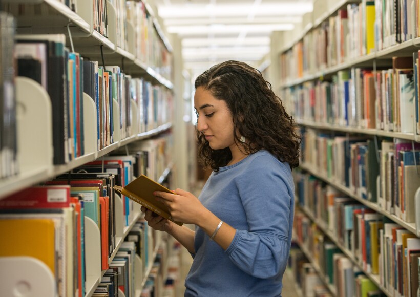 BYU-Idaho student, Karen Torres in the McKay Library, looking at a book