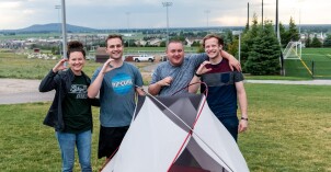 BYU-Idaho students smile while helping special needs students build a camping tent.