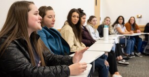 Students sitting at desks, in a circle in class