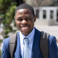 A male BYU-Idaho student dressed in a suit and necktie smiles for a photograph.