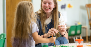 A child development student paints with a young girl.