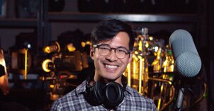 A Video Production student holds a mic and other equipment while smiling.