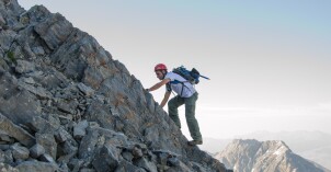 A man scales the side of a mountain.