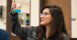 A female BYU-Idaho Biomedical Science student observes a chemical reaction during an experiment