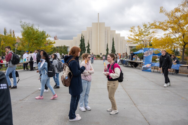 Societies from across campus gather in the MC Taylor quad to recruit and inform students of who they are and what they do. Students standing in a group, eating popsicles, talking to one another. 