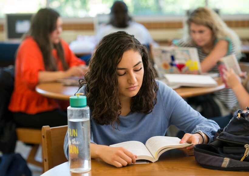 A BYU-Idaho student sitting at a table reading a book