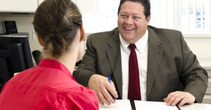 A BYU-Idaho student talking to a faculty member at their desk