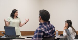 A female faculty member teaches a class of students about public health education and promotion.