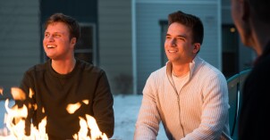 Two male students smile and laugh around a fire pit in one of the residential communities at BYU-Idaho.