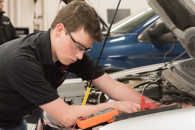 A student works on a car in an Advanced Vehicle Systems Lab.