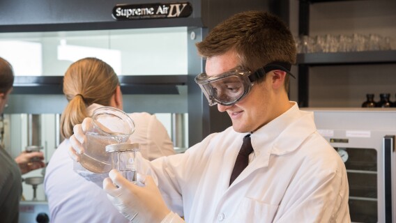 A male student working on a project in the Food Science Research Lab with two other students in the background.
