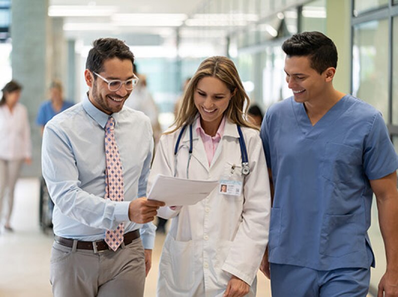 Three healthcare professionals looking at documents and smiling.