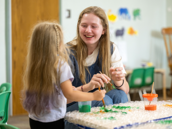 A child development student paints with a young girl