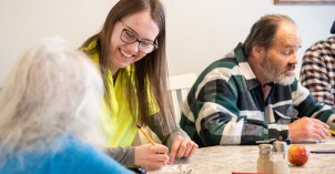 A BYU-Idaho student smiles while playing a game with an elderly woman at a Adopt-a-Grandparent I-Serve event.