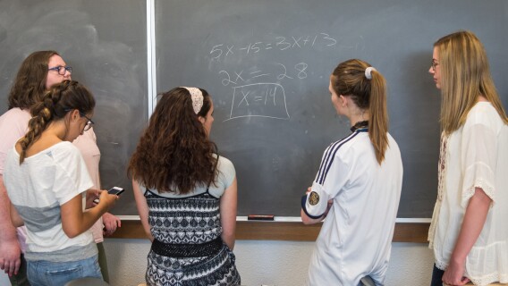 Student solve an equation on a chalkboard for their Math for the Real World class.