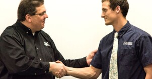 Two men shake hands.